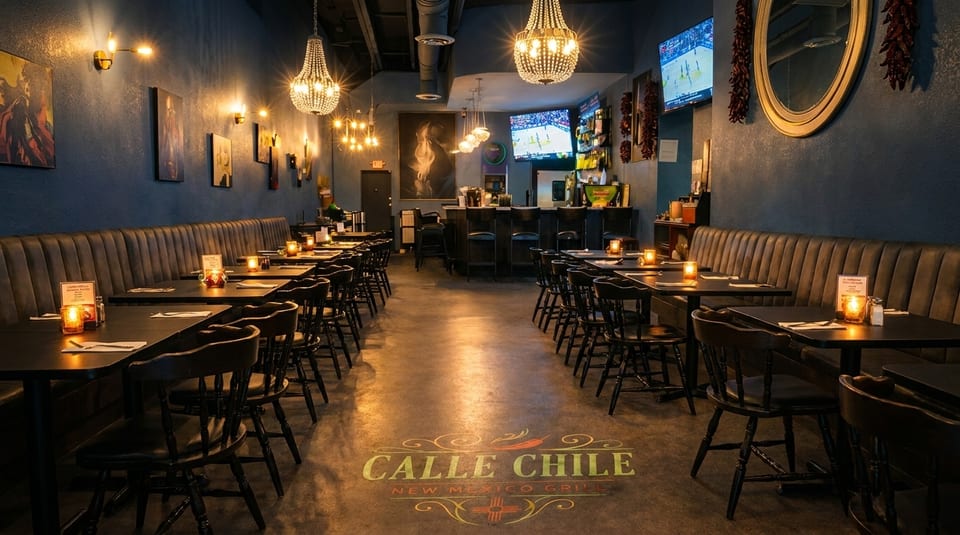 Interior of Calle Chile New Mexico Grill, showing dining tables, booths, a bar, and chandeliers.